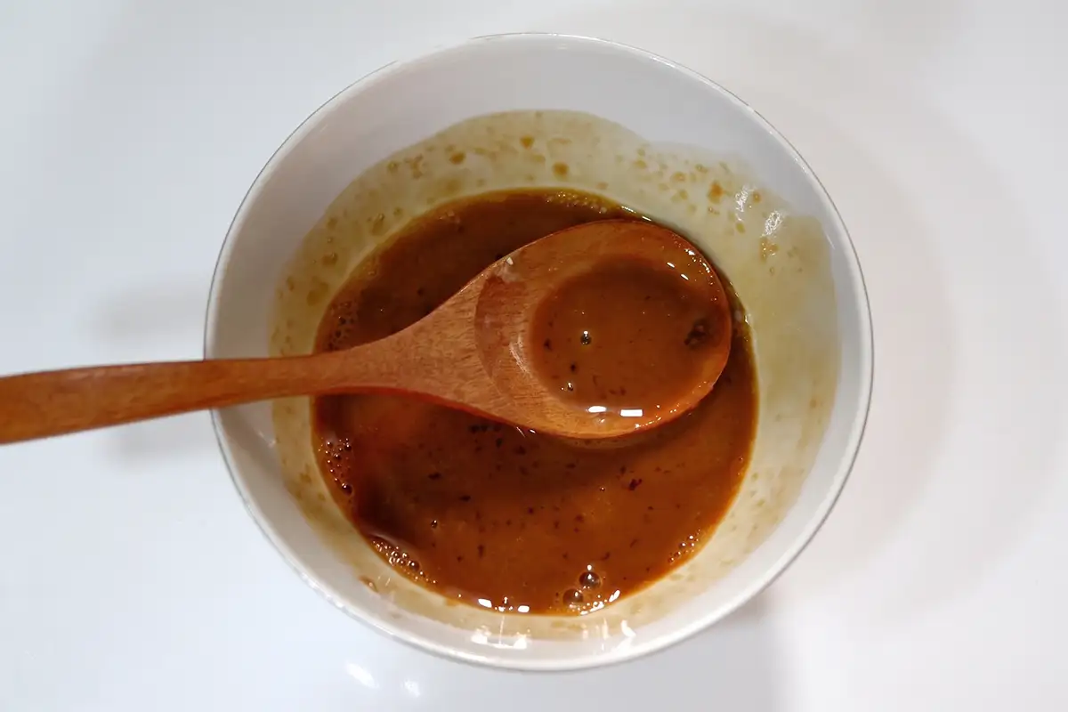 Pre-mixed Yu Xiang sauce in a small white bowl with a wooden spoon resting inside