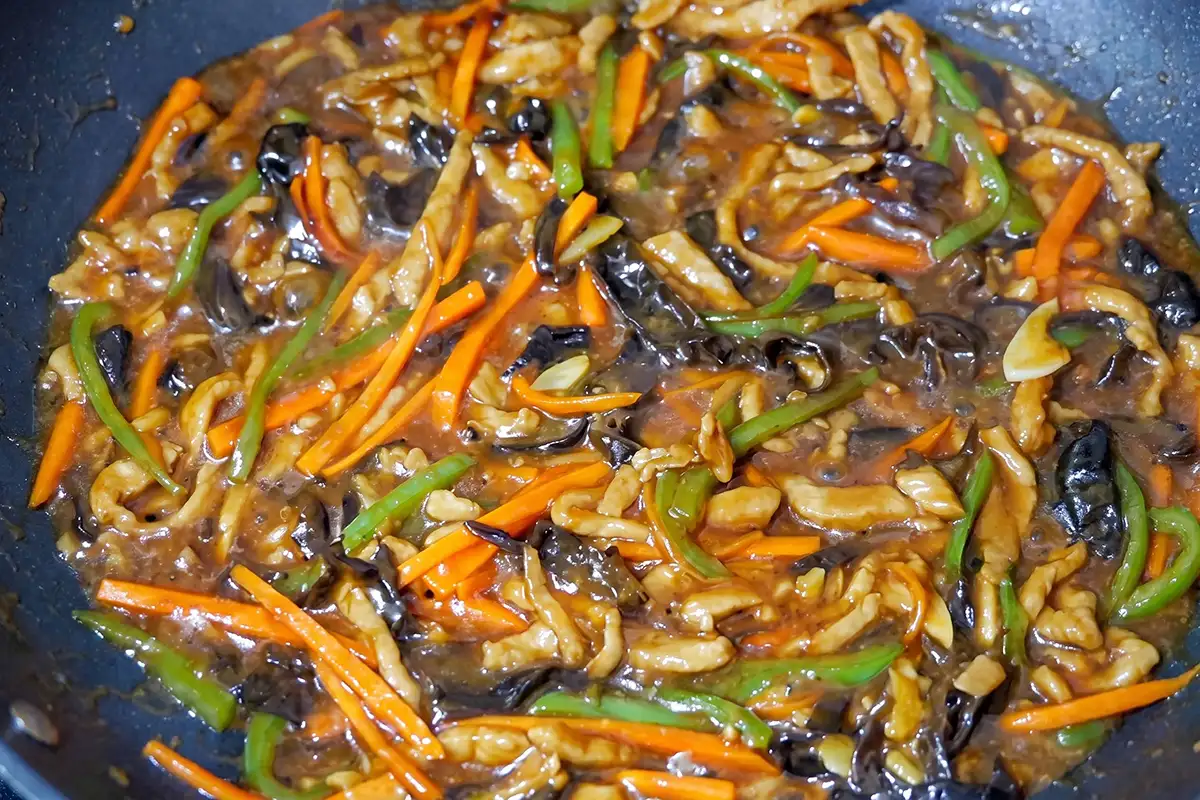 Finished Yu Xiang Rou Si in a wok: glossy shredded pork and vegetables coated in savory sauce